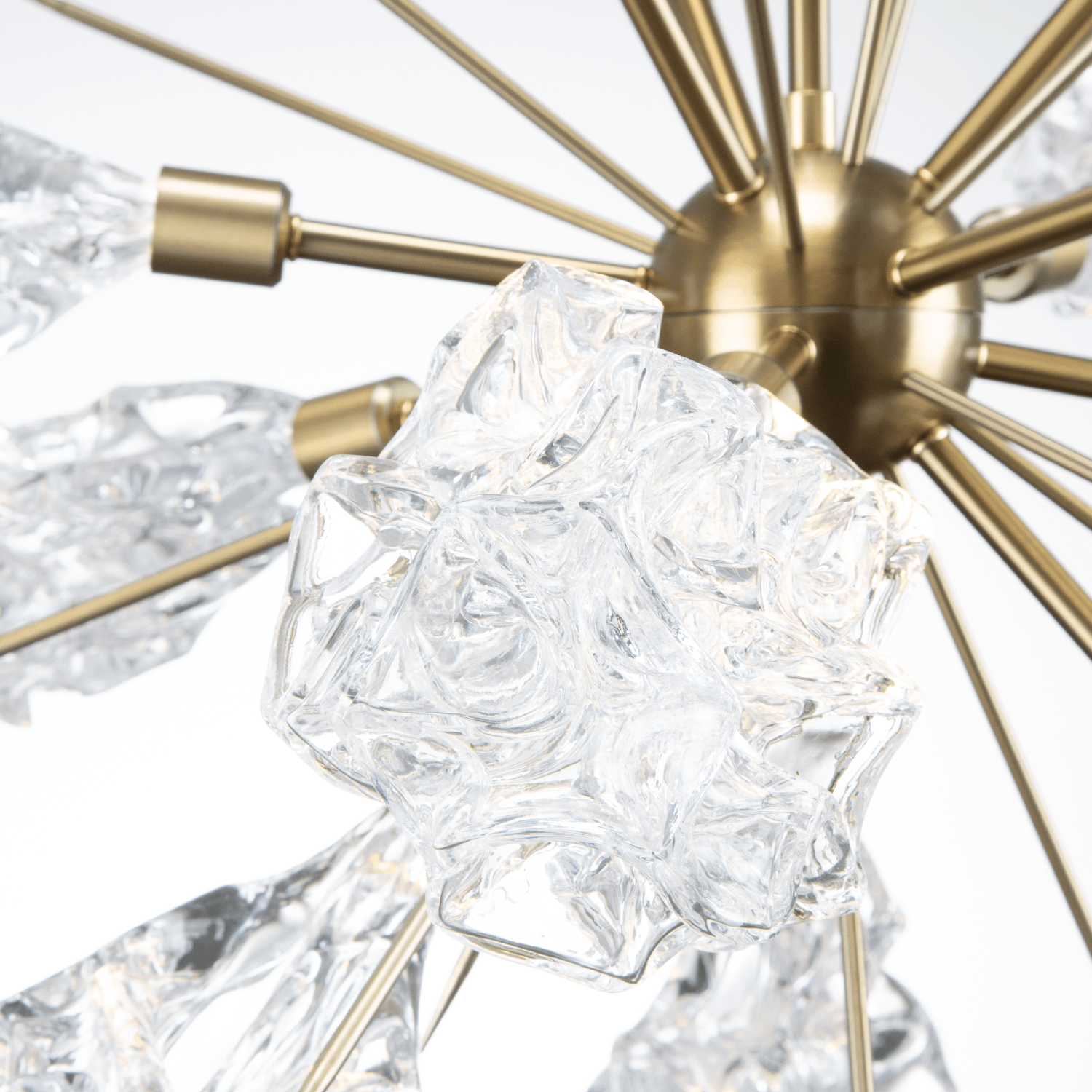 Closeup detail of a Hammerton Studio Blossom starburst chandelier with brass finish and blossom-shaped crystal glass light shades.