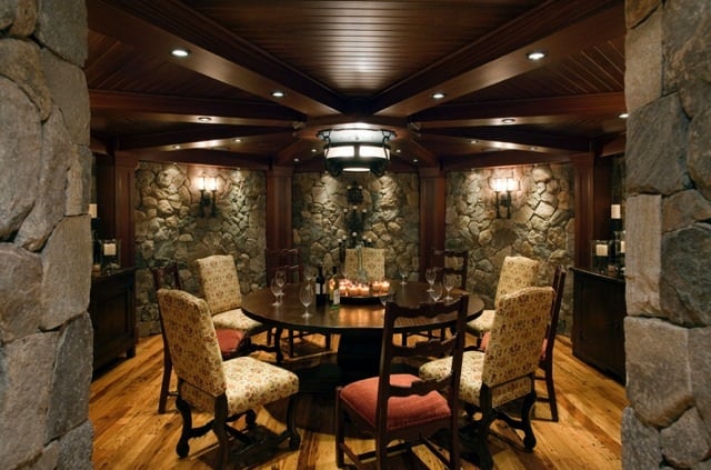 Double-light sconces echo the design elements of the central ceiling fixture and wash the stone walls with light, enlarging the room and highlighting the room's stunning finish details.