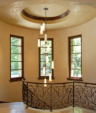 A spiraling fixture of sienna-tinted blown glass echoes the scrollwork in the surrounding stairway railing. Interiors by Alison Whittaker Design Inc.