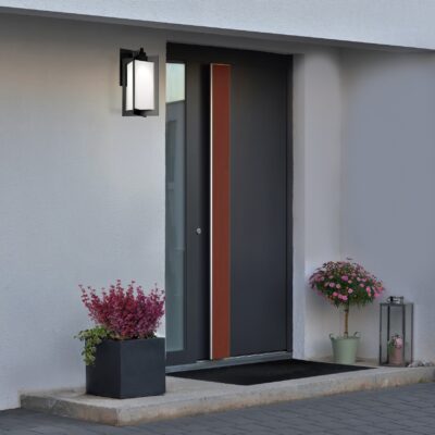 A large gray pot with a green bush in front of the entrance to the house next to the front gray door.