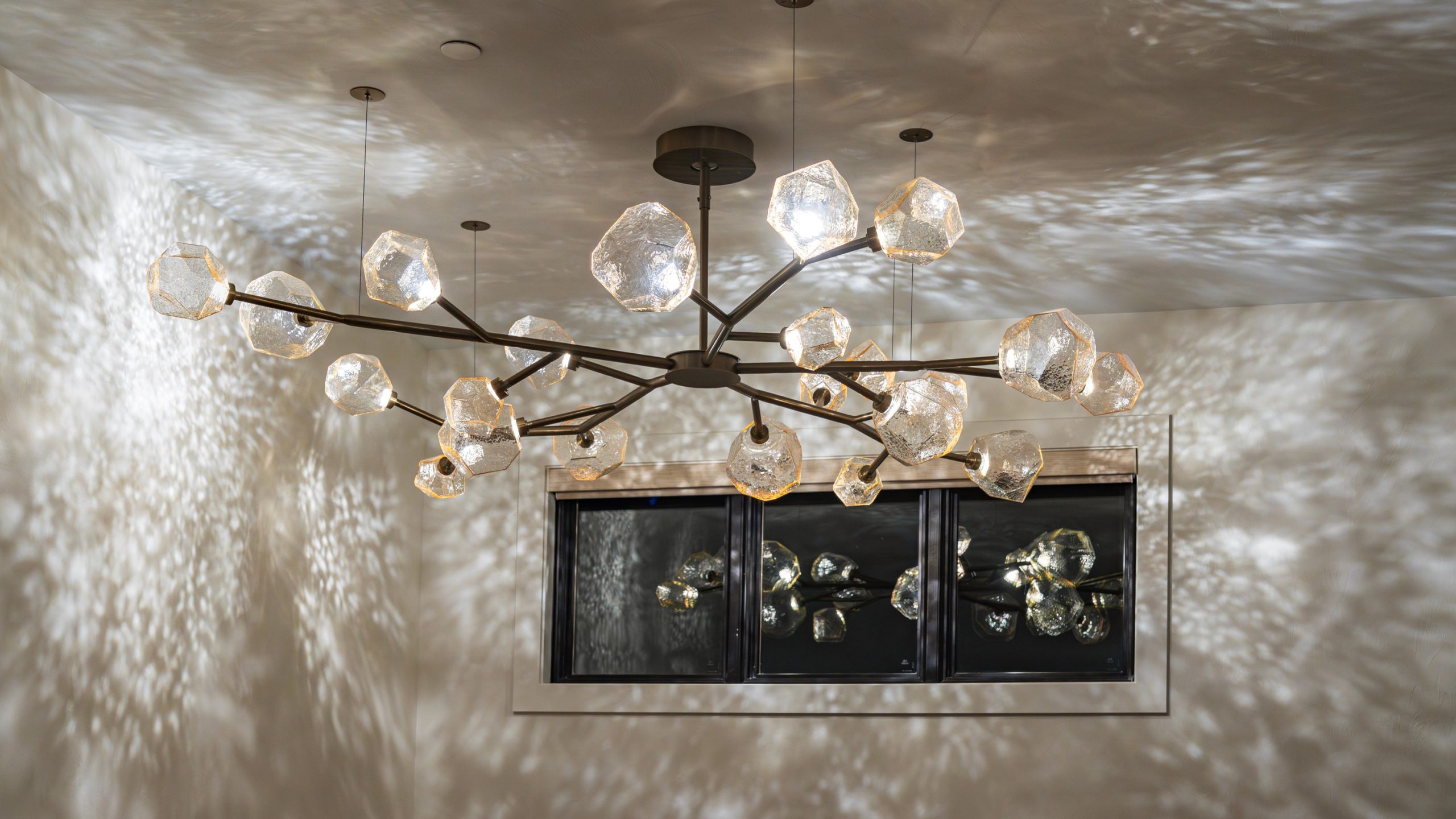 Fascinating light caustics reflecting on the walls from a custom branching chandelier with Hammerton Gem glass.